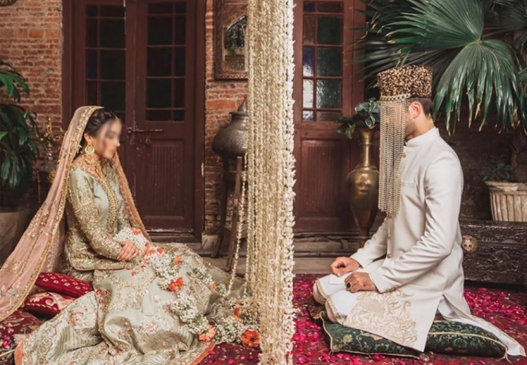 Bride and groom seated for a Nikkah ceremony with a floral divider at a Muslim wedding venue