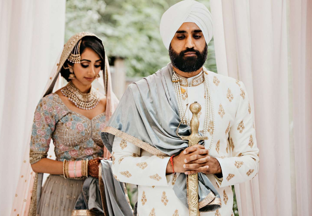 Sikh groom in turban with kirpan beside the bride at a London wedding venue